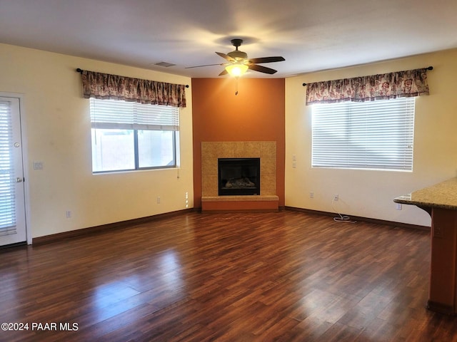 unfurnished living room featuring dark hardwood / wood-style floors, ceiling fan, and a fireplace