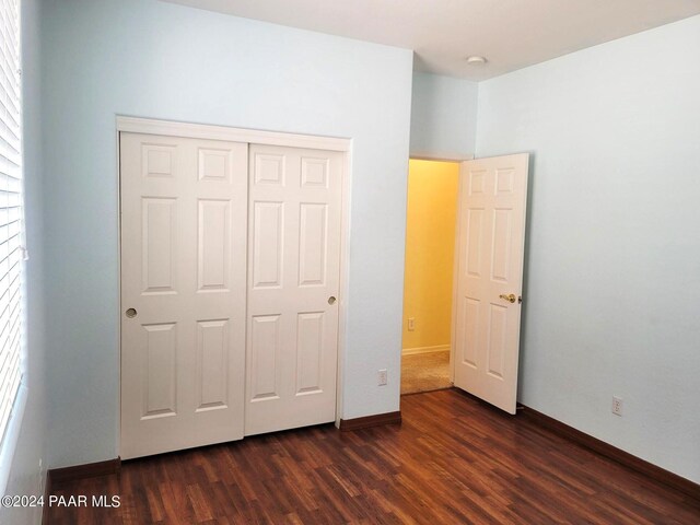 unfurnished bedroom featuring a closet and dark wood-type flooring