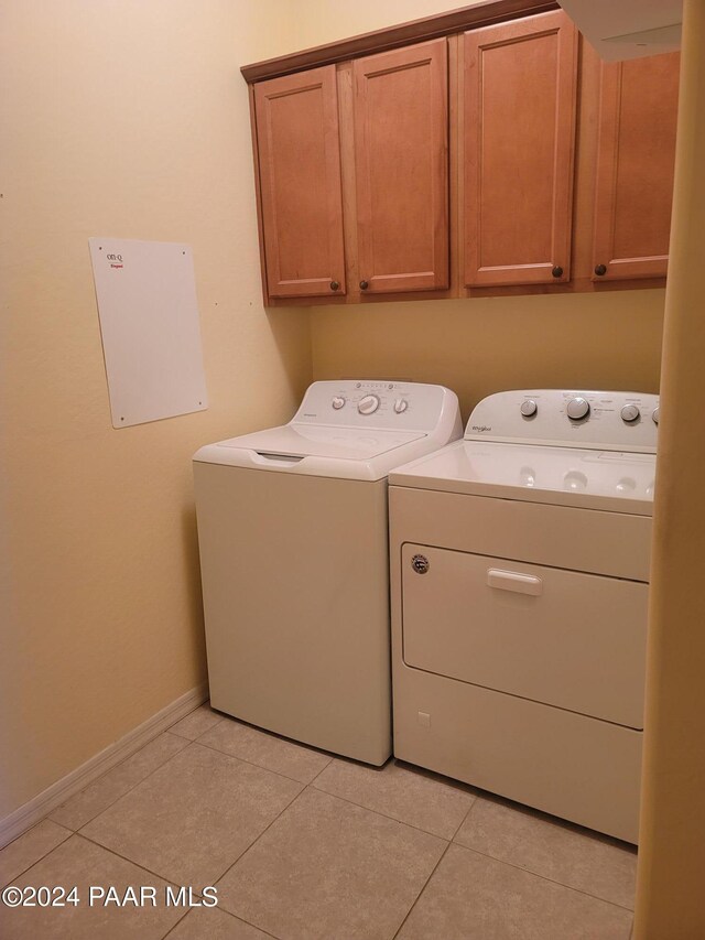 laundry area featuring cabinets, washing machine and dryer, and light tile patterned floors