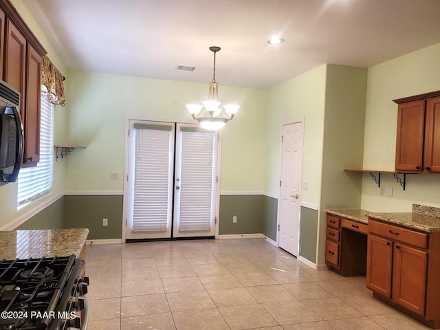 kitchen featuring pendant lighting, an inviting chandelier, light stone countertops, light tile patterned flooring, and gas stove