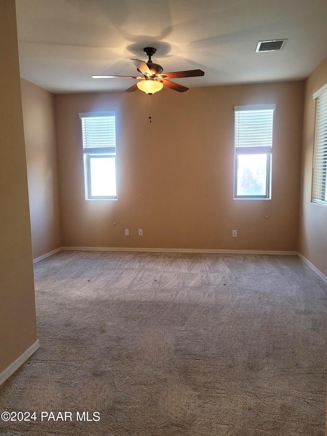 unfurnished room with plenty of natural light, ceiling fan, and light carpet