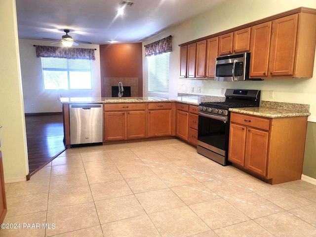 kitchen with sink, ceiling fan, light tile patterned floors, kitchen peninsula, and stainless steel appliances