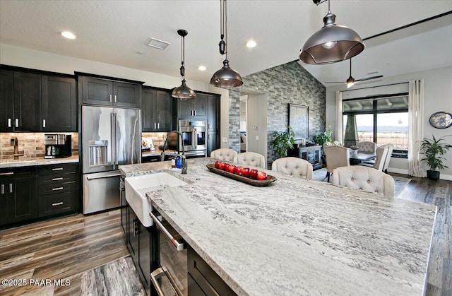 kitchen featuring a sink, light stone counters, stainless steel appliances, and dark wood finished floors