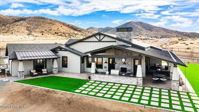 rear view of property with a patio, a standing seam roof, a mountain view, and an outdoor living space