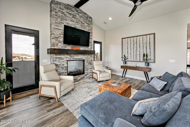 living area with a ceiling fan, a brick fireplace, wood finished floors, and a healthy amount of sunlight