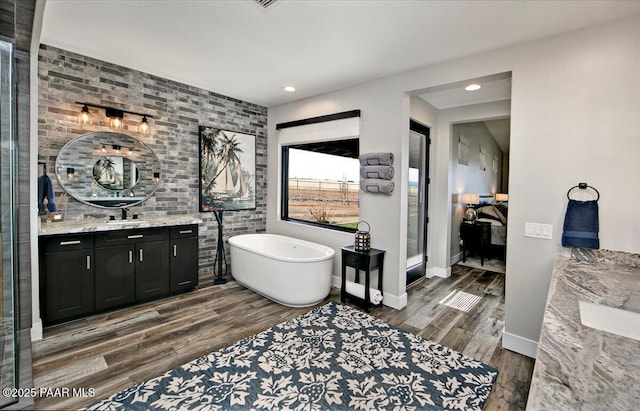 bathroom featuring vanity, recessed lighting, a freestanding tub, and wood finished floors