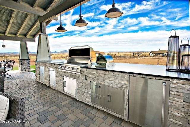 view of patio with fence, a grill, and exterior kitchen