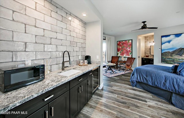 bedroom with beverage cooler, a sink, connected bathroom, and wood finished floors