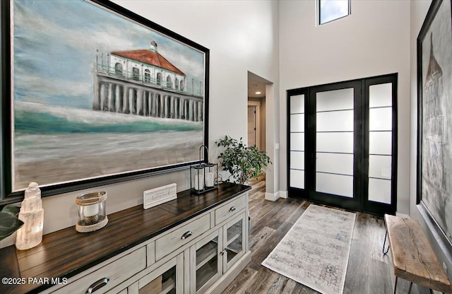 foyer with baseboards, dark wood finished floors, and a towering ceiling