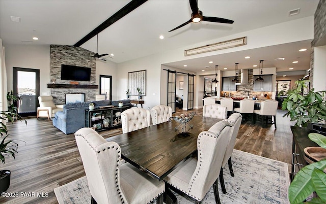 dining area with a barn door, a ceiling fan, vaulted ceiling with beams, a wealth of natural light, and visible vents