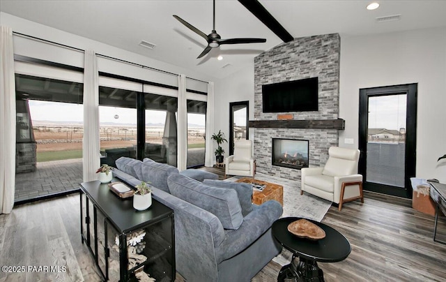 living area with a large fireplace, ceiling fan, wood finished floors, and visible vents