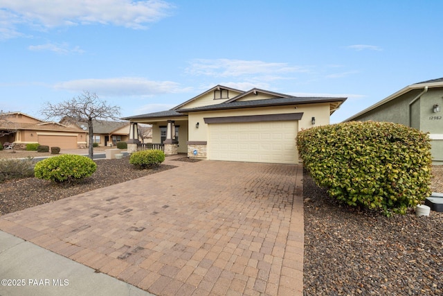 view of front of property with covered porch, stone siding, stucco siding, an attached garage, and decorative driveway