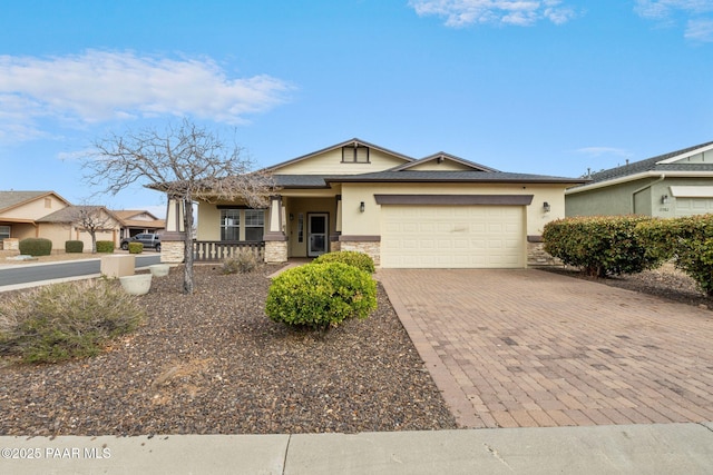 view of front facade with stucco siding, an attached garage, stone siding, decorative driveway, and covered porch