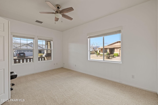 carpeted spare room featuring baseboards, ceiling fan, and visible vents