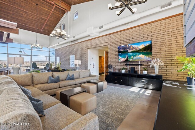 living room featuring a chandelier, a high ceiling, finished concrete floors, brick wall, and visible vents