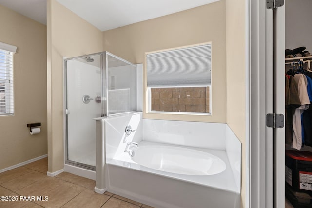 full bathroom with tile patterned flooring, a spacious closet, baseboards, a shower stall, and a garden tub