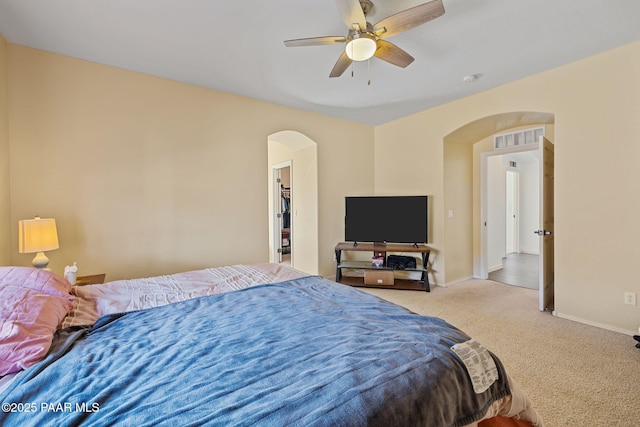 bedroom featuring carpet floors, arched walkways, baseboards, and visible vents