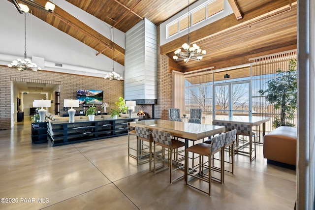 dining room with concrete floors, a notable chandelier, high vaulted ceiling, and a fireplace