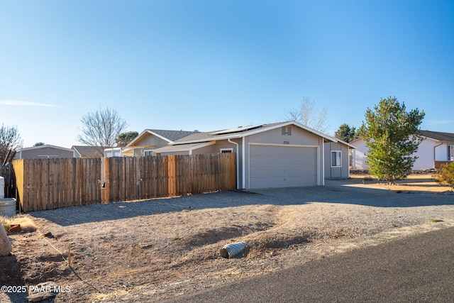 view of front facade featuring solar panels, fence, a garage, and driveway