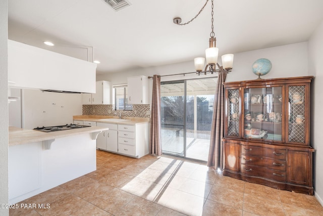 kitchen with a sink, visible vents, white cabinets, and light countertops