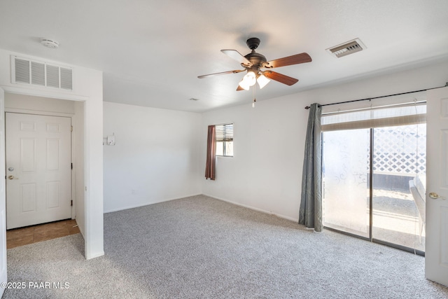 carpeted spare room with visible vents and ceiling fan