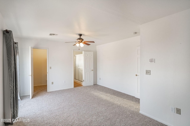 empty room featuring visible vents, light colored carpet, baseboards, and a ceiling fan