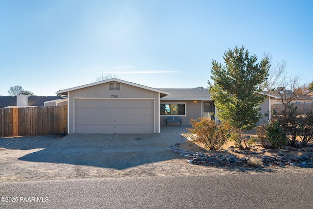 ranch-style house featuring driveway, an attached garage, and fence