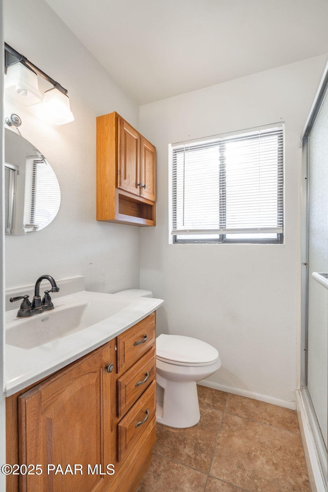 bathroom featuring vanity, toilet, baseboards, and a shower with door