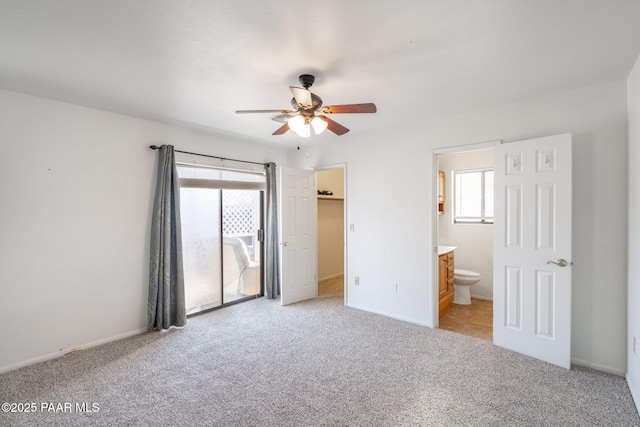 unfurnished bedroom featuring a walk in closet, multiple windows, light carpet, and ensuite bathroom