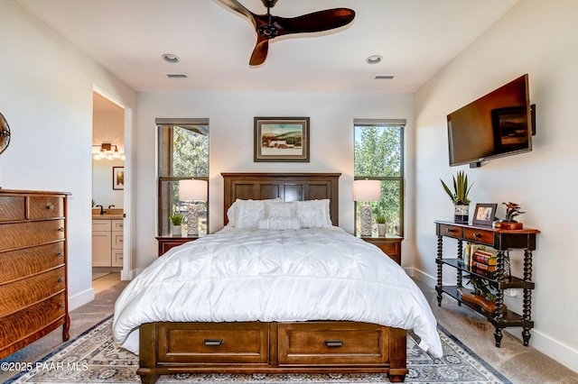 carpeted bedroom with connected bathroom, ceiling fan, and multiple windows