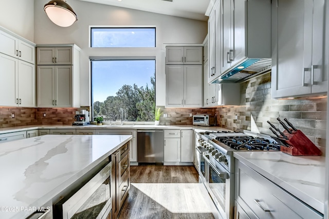 kitchen with light stone counters, plenty of natural light, vaulted ceiling, and appliances with stainless steel finishes