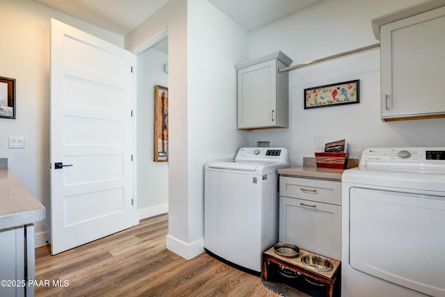 laundry area with cabinets, light hardwood / wood-style flooring, and washer and dryer