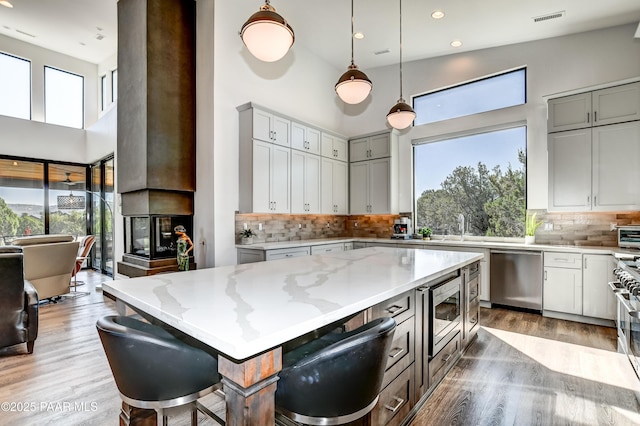 kitchen with a breakfast bar, a center island, decorative backsplash, light stone counters, and stainless steel appliances