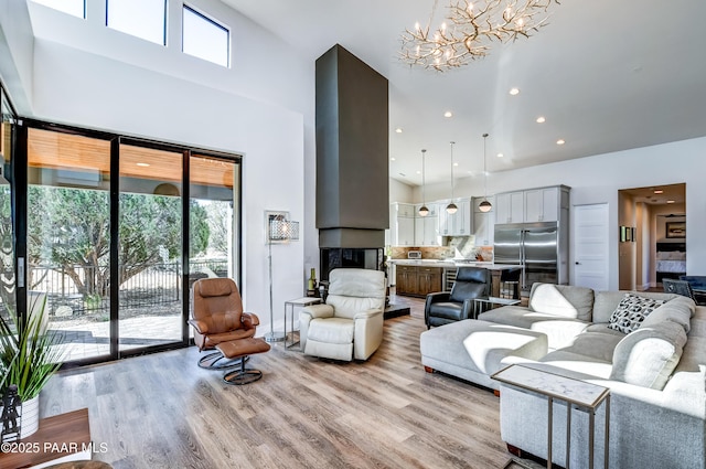 living room with a notable chandelier, a high ceiling, and light hardwood / wood-style flooring