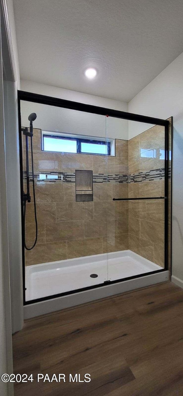 bathroom featuring hardwood / wood-style flooring, an enclosed shower, and a textured ceiling