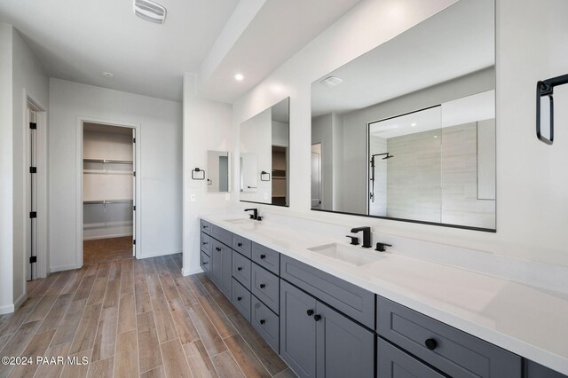 bathroom with hardwood / wood-style floors, vanity, and tiled shower