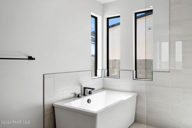 bathroom featuring a bathtub and tile walls