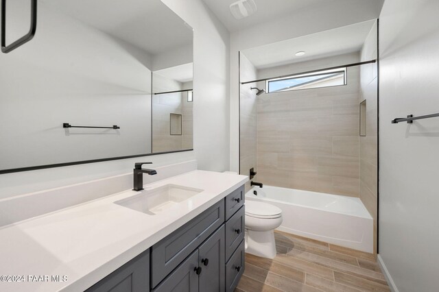 full bathroom featuring vanity, tiled shower / bath combo, and toilet