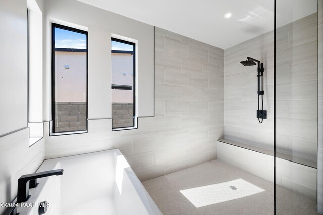 bathroom with tile walls and independent shower and bath