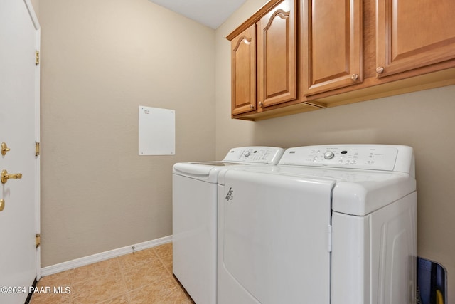 laundry area with cabinets, light tile patterned floors, and washing machine and clothes dryer