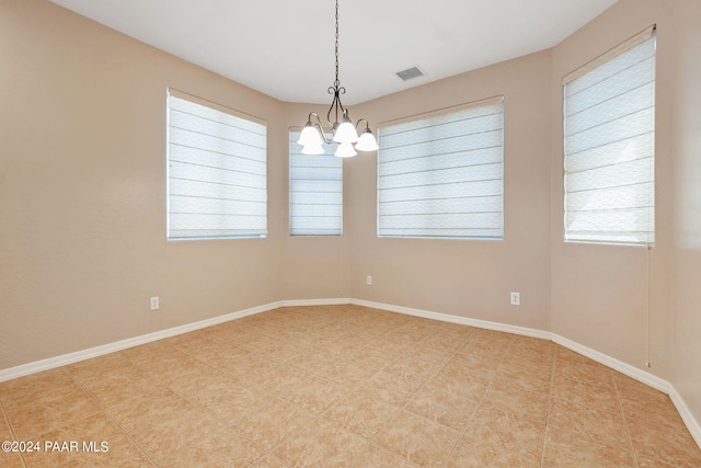 spare room with plenty of natural light and a notable chandelier