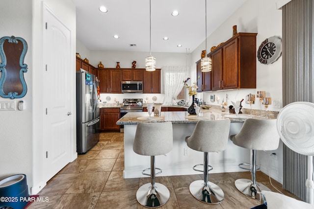 kitchen featuring pendant lighting, a breakfast bar area, light stone counters, a peninsula, and stainless steel appliances