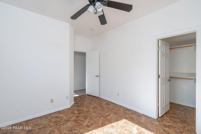 unfurnished bedroom with a walk in closet, a closet, and ceiling fan