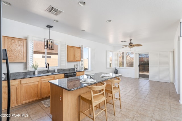 kitchen with sink, dark stone countertops, black dishwasher, a kitchen island, and pendant lighting