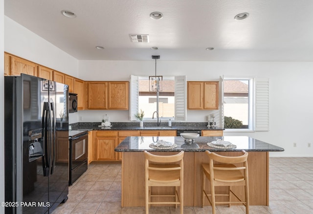 kitchen featuring a center island, sink, hanging light fixtures, and black appliances