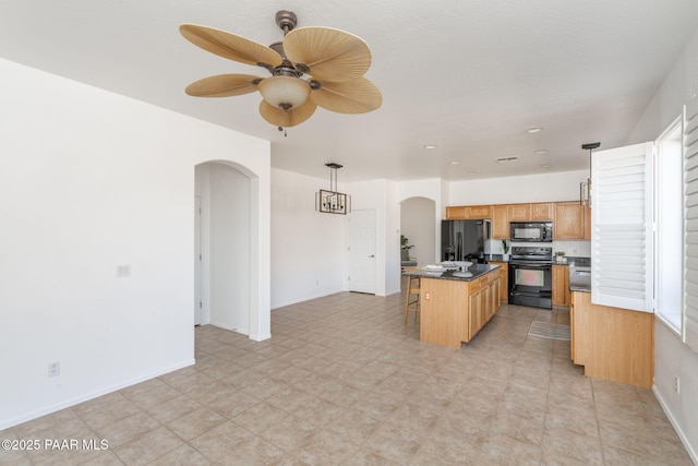 kitchen featuring pendant lighting, a breakfast bar area, ceiling fan, a center island, and black appliances