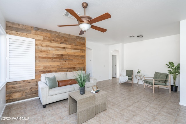 living room with ceiling fan and wooden walls