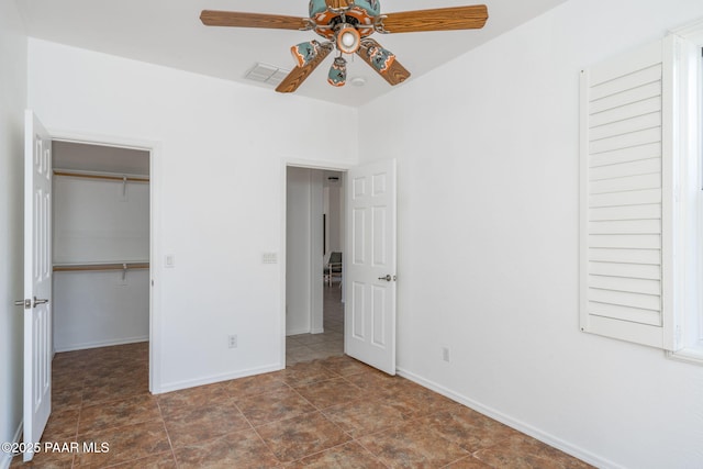 unfurnished bedroom with ceiling fan, a spacious closet, and a closet