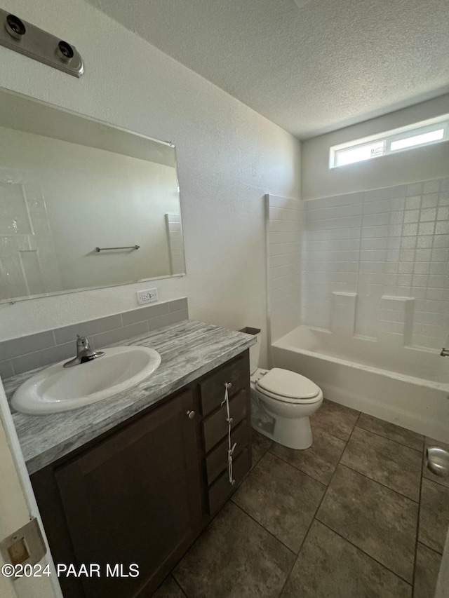 full bathroom featuring a textured ceiling, vanity, bathing tub / shower combination, tile patterned flooring, and toilet