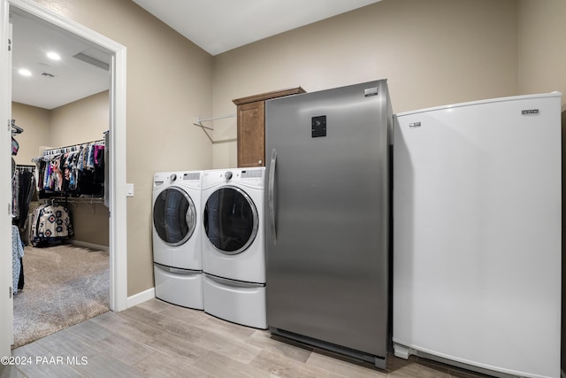 laundry area with independent washer and dryer and light wood-type flooring